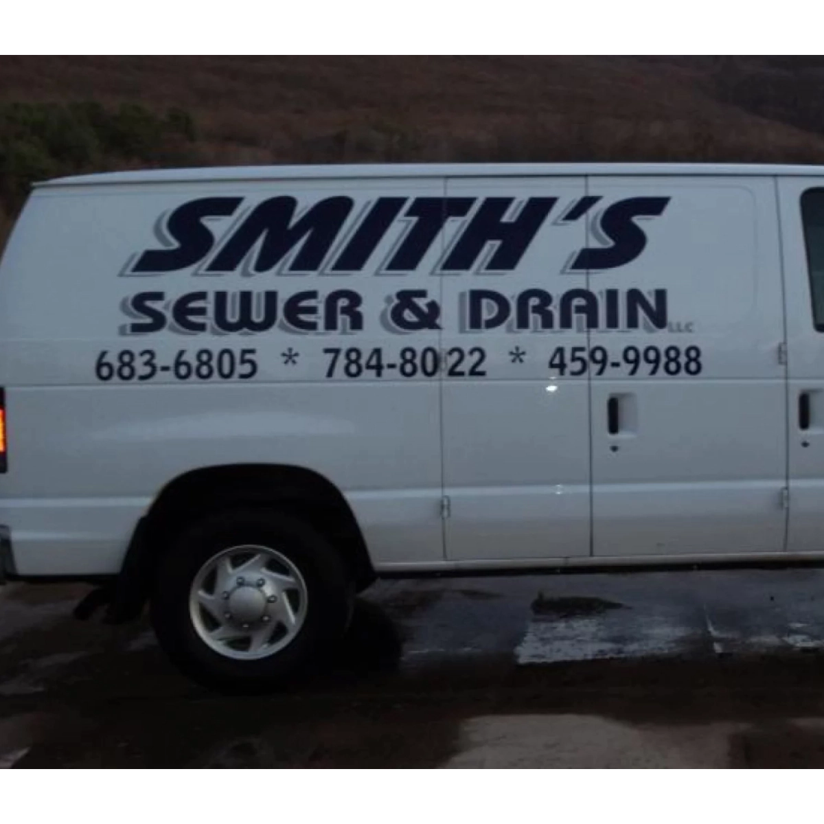 white van with the smiths logo and information and a mountain behind